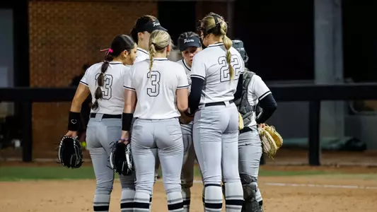 Softball Team huddle at the Raleigh Times Tournament against NC State