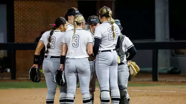 Softball Team huddle at the Raleigh Times Tournament against NC State