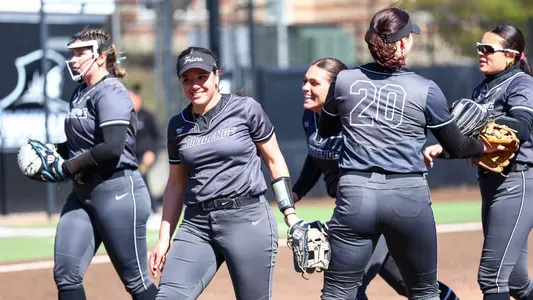 The 2026 Softball infield celebrates as a group at the end of an inning.