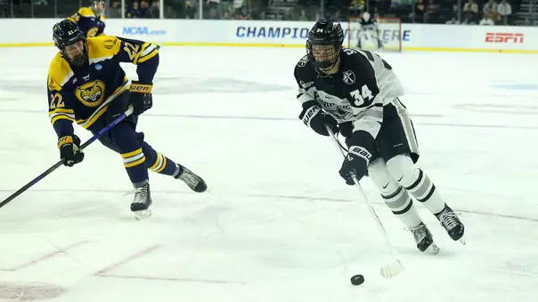 Men's ice hockey player Logan Sawyer skating with the puck during a game
