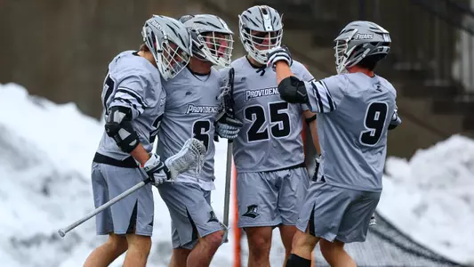 Mens lacrosse players together celebrating goal versus Brown at Chapey Field at Anderson Stadium.