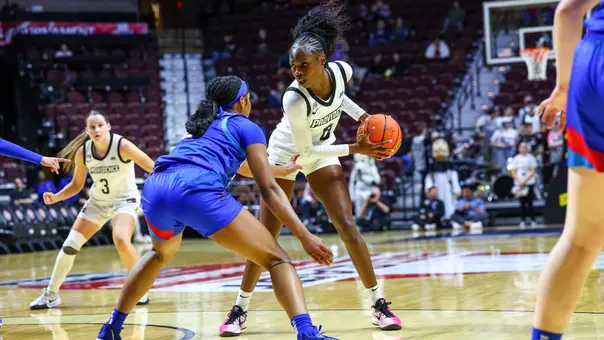 Sabou Gueye holds the basketball in the triple-threat position at the top of the key while being defended by a player from DePaul