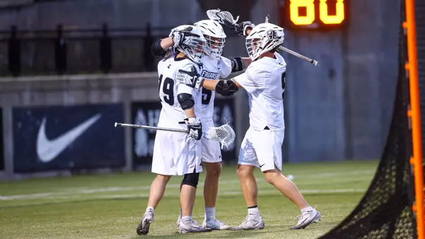 Mens Lacrosse celebrates a goal versus Villanova in the BIG EAST Semifinals wearing white jerseys with white helmets on Chapey Field at Anderson Stadium.
