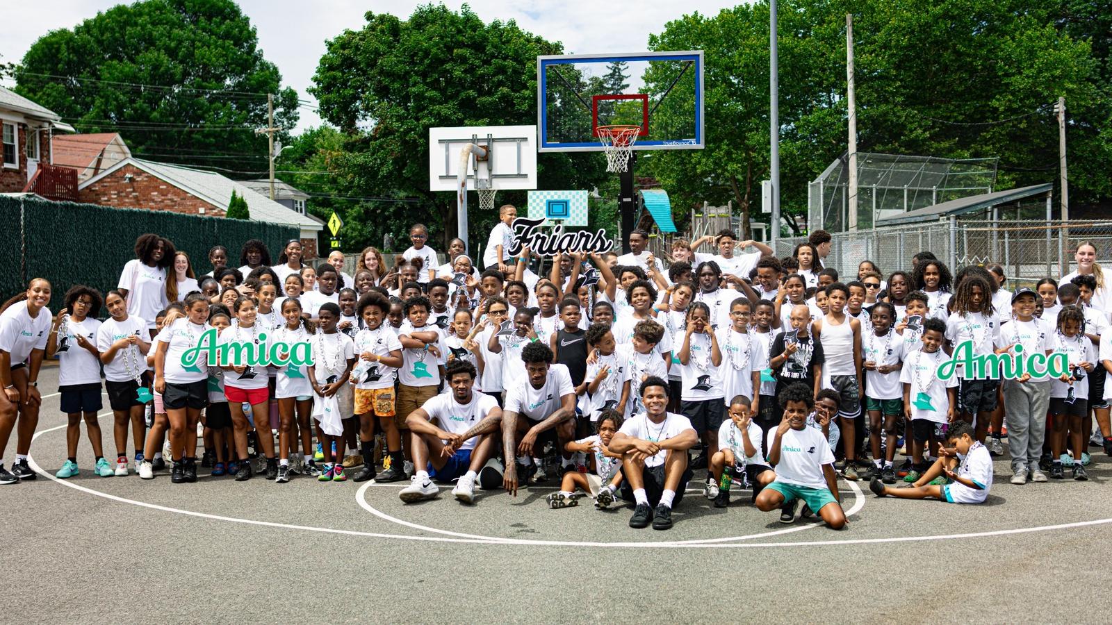 A group picture with the men's and women's basketball teams and the Providence Recreation Department Summer Program during a summer clinic
