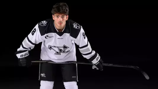 JJ Monteiro Men's Hockey leaning down on stick