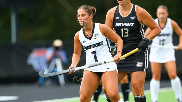 Lily Procaccianti stands in front of a Bryant defender holding her field hockey stick in front of her.