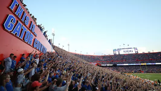 Gator fans fill The Swamp. This is Gator Country signage is behind them on the left and football field on the right.