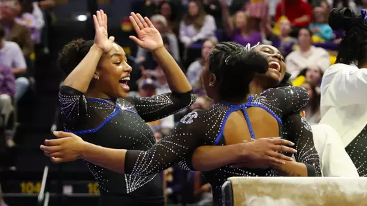 Bri Edwards (left) and Taylor Clark celebrate Selena Harris-Miranda's (back to camera) balance beam routine at LSU 250117.