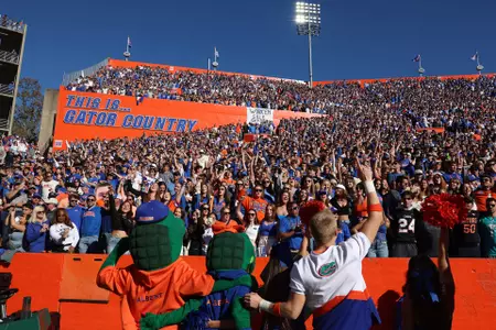 Cheerleaders and mascots lead fans in cheer in front of This Is Gator Country signage