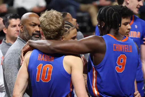Thomas Haugh and Rueben Chinyelu talk on the sideline with associate head coach Carlin Hartman.