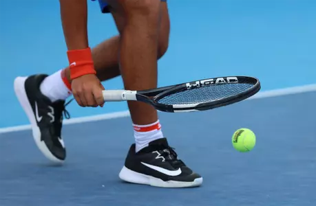 A closeup shoe shot of a Florida tennis player (Adhithya Ganesan) using his racquet to bounce a tennis ball.
