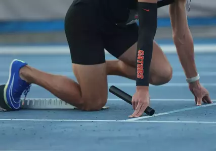 A male is in the starting blocks in a black uniform that says Gators