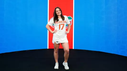 Gators Transfer Angie Conley in white jersey in front of Gator Logo