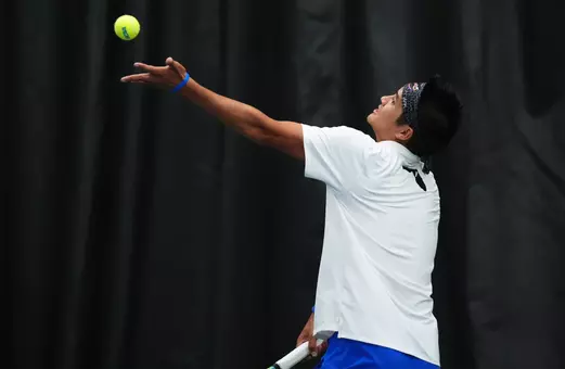Tanapatt Nirundorn tossing the tennis ball in the air for his serve in doubles against UCF in NCAA Second Round.