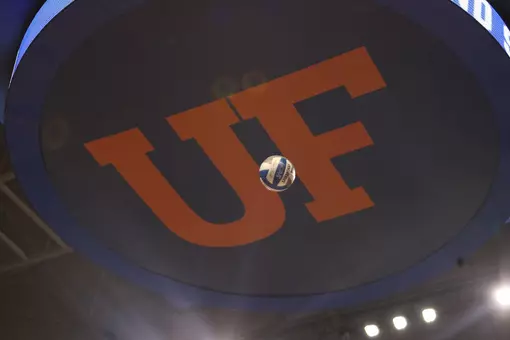 A blue and white volleyball is hovering below a blue canvas with orange letters UF.