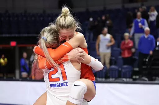 Two female volleyball athletes, one in white and one in orange Florida uniforms, hugging