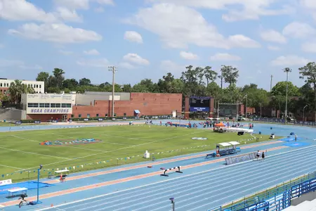 An outdoor track and field complex with a blue track and green grass infield.