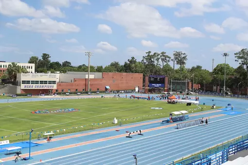 An outdoor track and field complex with a blue track and green grass infield.