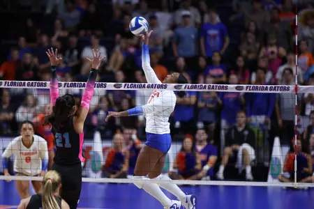 A Florida female athlete in a white volleyball jersey hits the ball