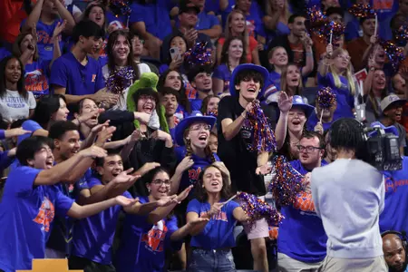 A group of fans in blue with clap and yell in front of tv camera