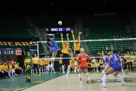 A Florida athlete in blue swings at a volleyball in a green arena