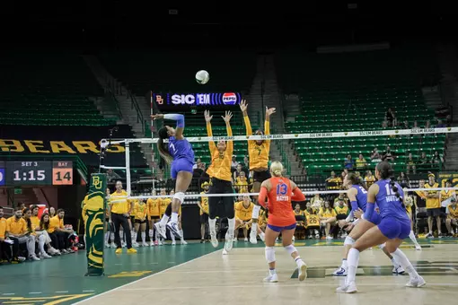 A Florida athlete in blue swings at a volleyball in a green arena