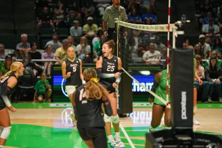 Female athletes in black Florida Gators jerseys celebrate after scoring a point in volleyball