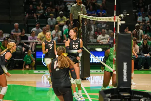 Female athletes in black Florida Gators jerseys celebrate after scoring a point in volleyball