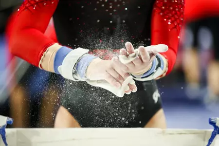 A gymnast chalks her hands during the First Look meet at Stegeman Coliseum in Athens, Ga., on Tuesday, Dec. 17, 2019. (Photo by Chamberlain Smith)
