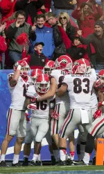 The team celebrates with McKenzie (16) after he returned the opening kickoff 90 yards for a touchdown against Kentucky.