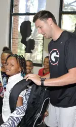 Track and field athlete Burke McCarty gives a backpack to one of the students at D.H. Stanton Elementary.