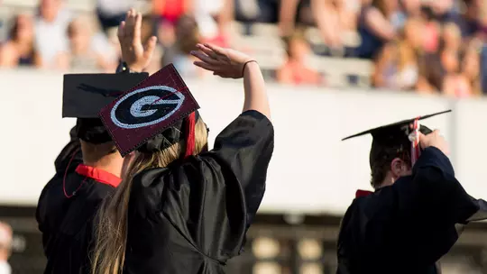 Undergraduate students wave to family and friends as they enter the Sanford Stadium field during the processional at the 2018 Spring Undergraduate Commencement Ceremony.