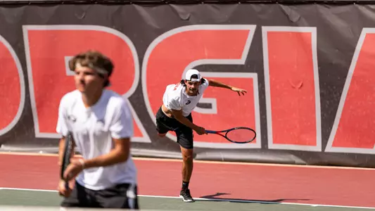 Blake Croyder serving in doubles alongside partner Britton Johnston.