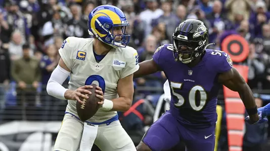 Jan 2, 2022; Baltimore, Maryland, USA; Los Angeles Rams quarterback Matthew Stafford (9) tripos back to pass as Baltimore Ravens outside linebacker Justin Houston (50) rushes during the first quarter at M&T Bank Stadium. Mandatory Credit: Tommy Gilligan-USA TODAY Sports