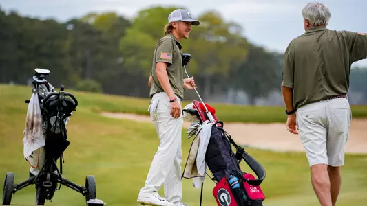 Freshman Camden Smith speaking with associate head coach Jim Douglas prior to taking a shot during the first round of the Linger Longer Invitational on March 17, 2024.