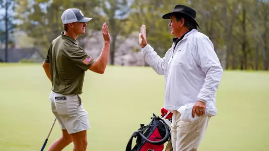 Head coach Chris Haack and sophomore Carter Loflin high-fiving during the first round of the Linger Longer Invitational.