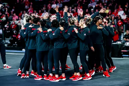 The Georgia Gymnastics team celebrates in a huddle.