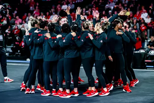 The Georgia Gymnastics team celebrates in a huddle.