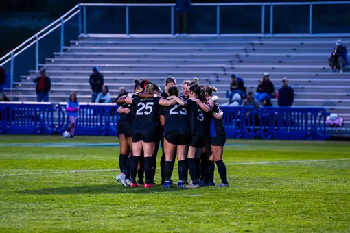 The women's soccer team huddles on the field