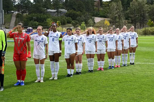 The women's soccer team salutes during the national anthem pregame