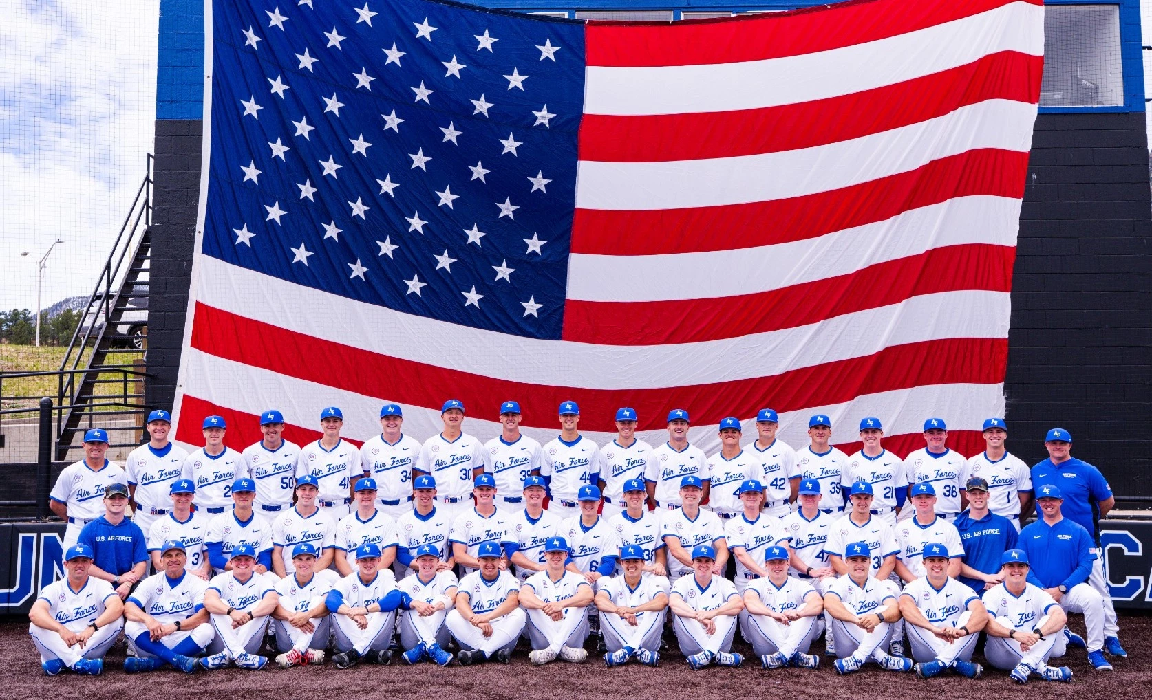 The 2026 baseball team poses for a team shot in front of a big American flag at Erdle Field