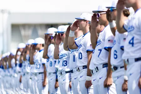 The baseball team salutes during the national anthem at Erdle Field.