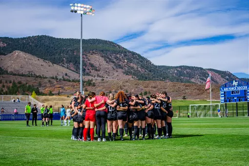 The women's soccer team huddles at Cadet Soccer Stadium before a game.