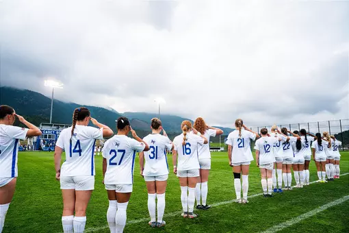 The women's soccer team salutes for the National Anthem before playing Army at Cadet Soccer Stadium.
