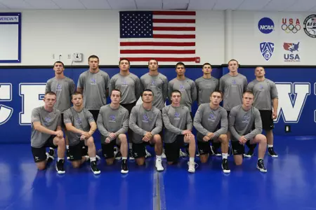 Air Force wrestling freshmen, with stern faces, pose for a group photo in the wrestling room