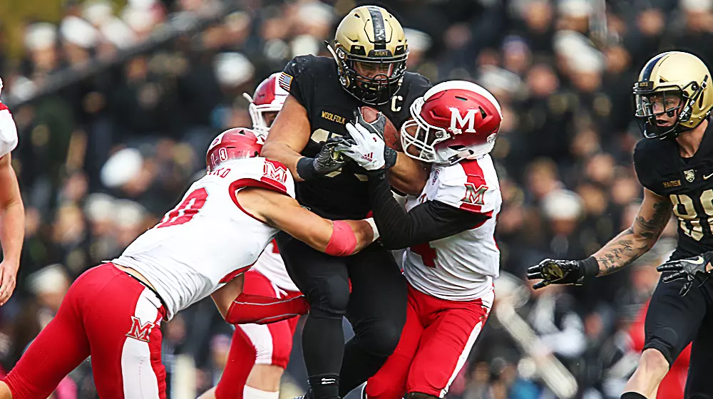 Darnell Woolfolk carries three Miami (OH) players down the field as he fights for yardage in a game for the Black Knights