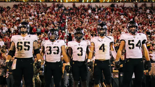 The game captains for Army Football against Oklahoma walk hand-in-hand out to center field for the coin toss