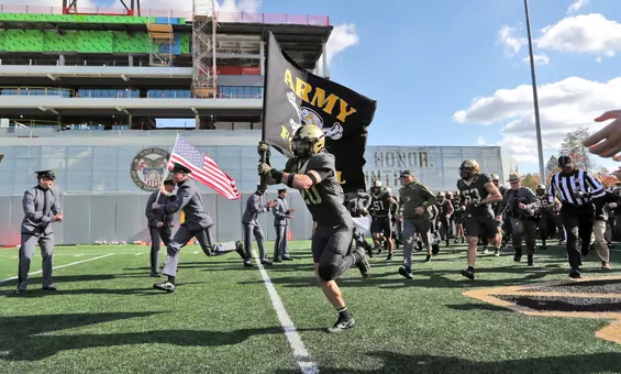 Nov 8, 2025; West Point, New York, USA; Army Black Knights safety Casey Larkin (20) leads his teammates out to the field with a flag before a game against the Temple Owls during the first half at Michie Stadium. Mandatory Credit: Danny Wild-Imagn Images