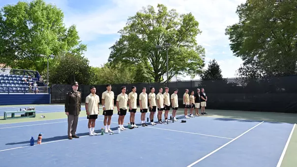 Army men's tennis stands at attention during playing of the West Point alma mater following tennis match against Navy