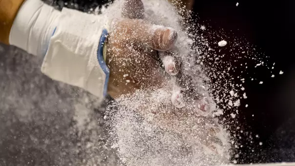 An Army Gymnast prepares to compete by rubbing chalk on his hands during the 2026 NCAA Championships